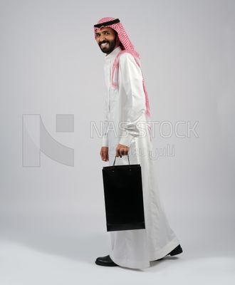 Gulf man carrying black shopping bag