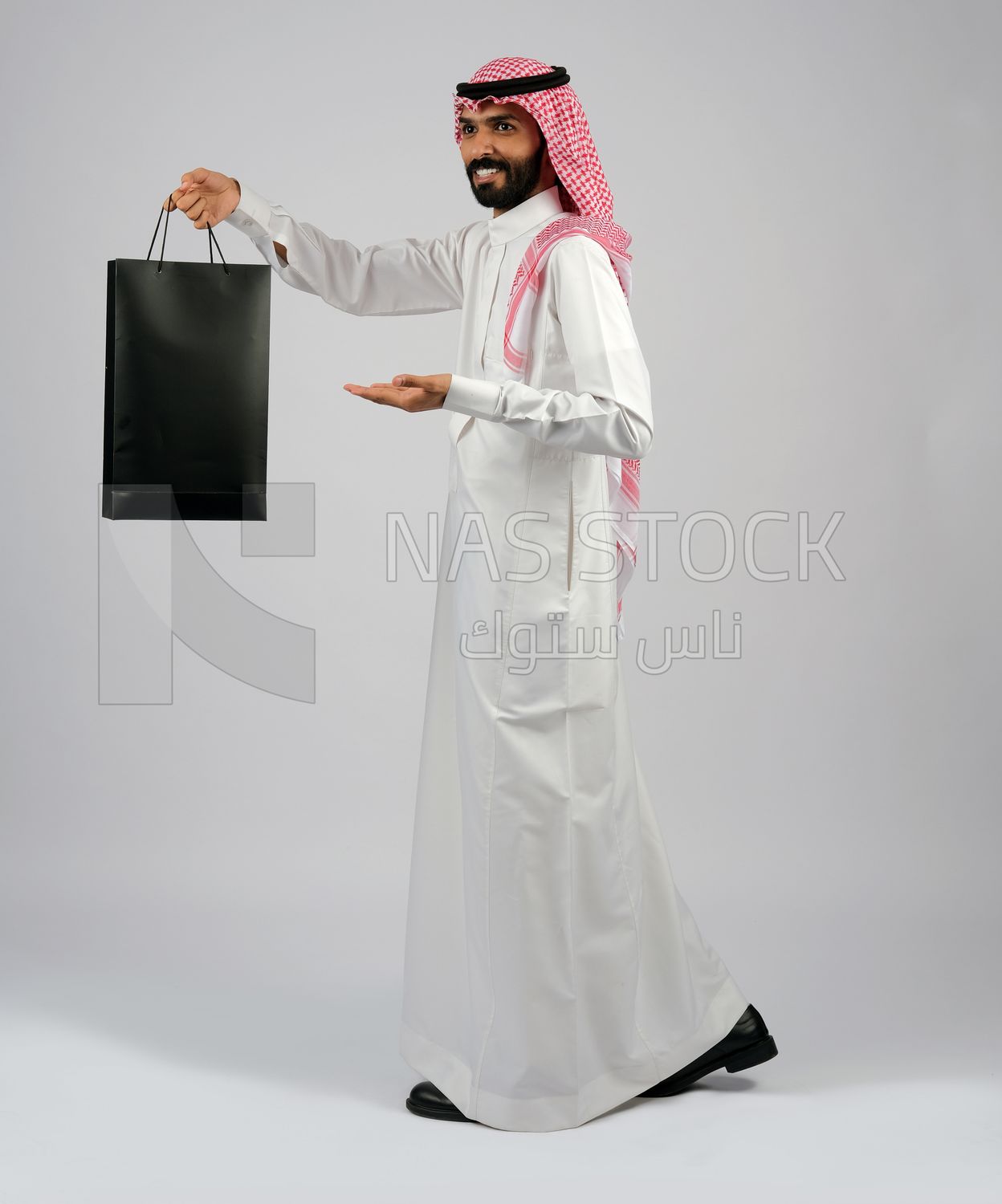 Gulf man carrying black shopping bag