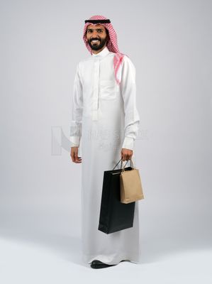 رجل خليجي يحمل حقيبة تسوق