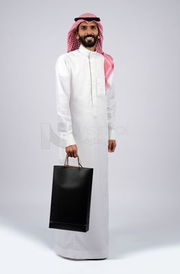 رجل خليجي يحمل حقيبة تسوق