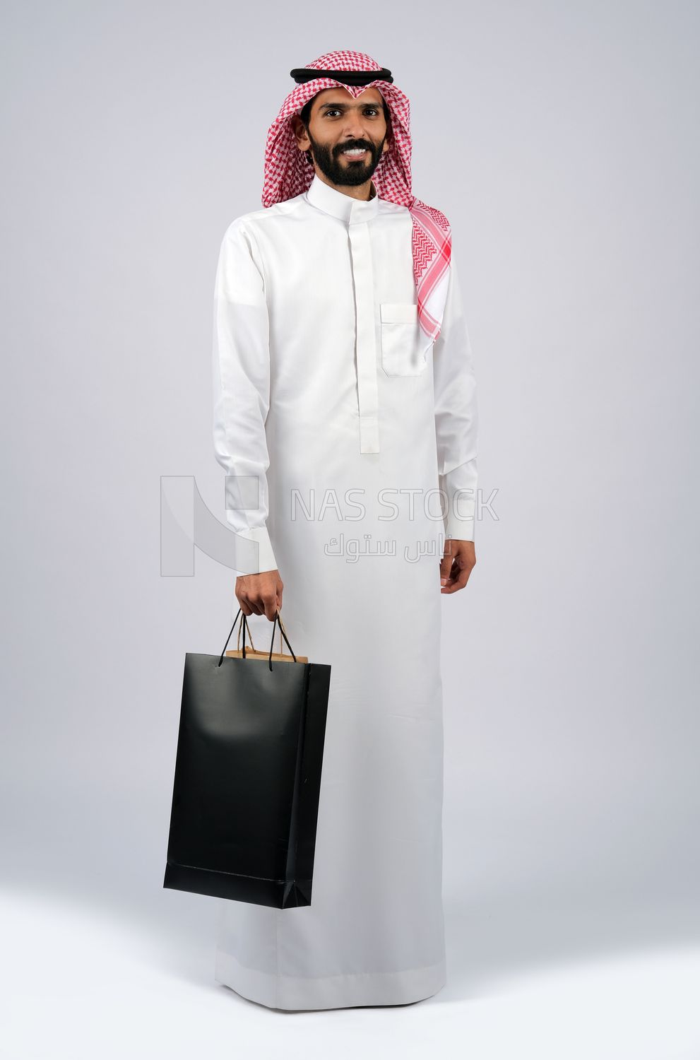 رجل خليجي يحمل حقيبة تسوق