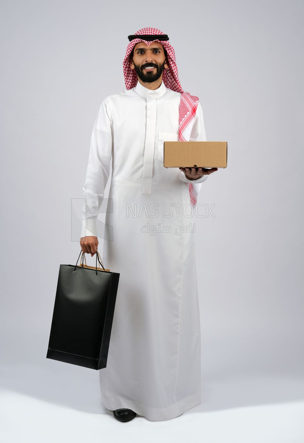 Gulf man holding a box and bags of purchases