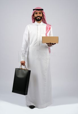 Gulf man holding a box and bags of purchases