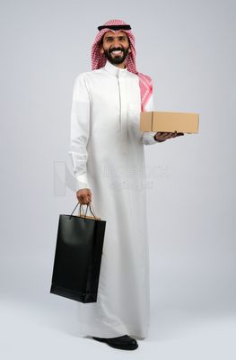 Gulf man holding a box and bags of purchases