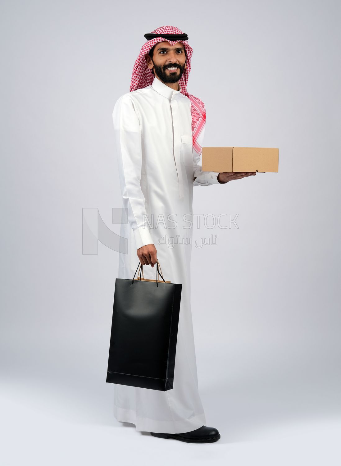 Gulf man holding a box and bags of purchases