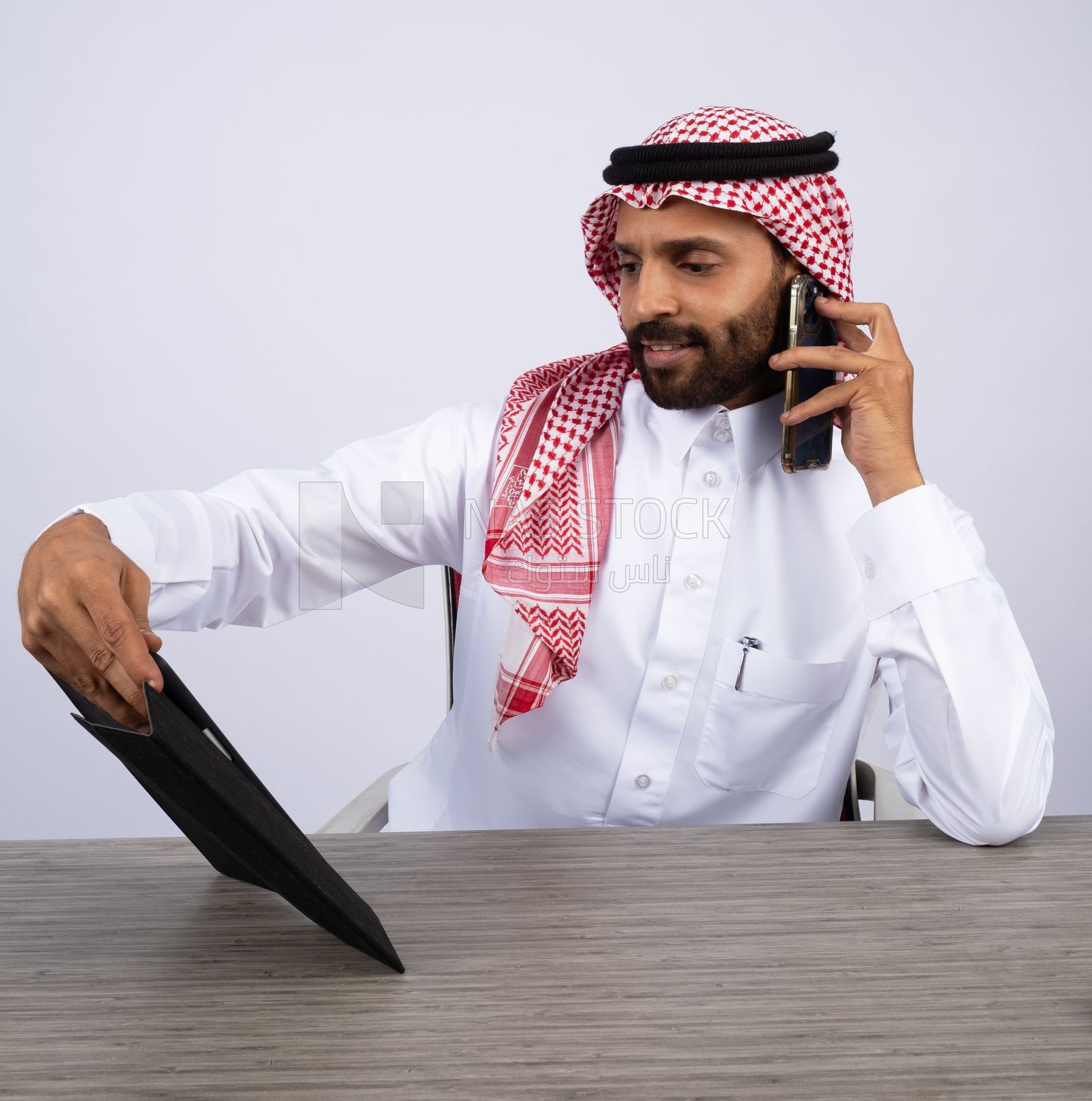 رجل خليجي يجري مكالمة ويستخدم جهاز لوحي