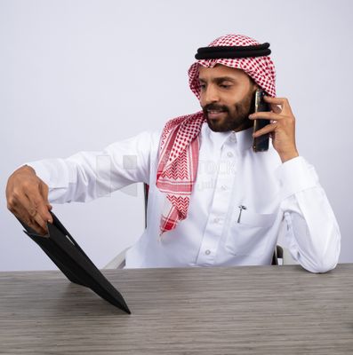رجل خليجي يجري مكالمة ويستخدم جهاز لوحي