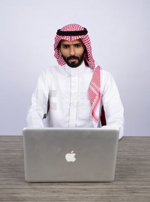 Gulf man sitting at desk using laptop