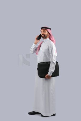 Gulf man carrying handbag and making a phone call
