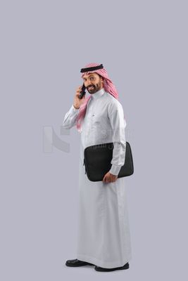 Gulf man carrying handbag and making a phone call