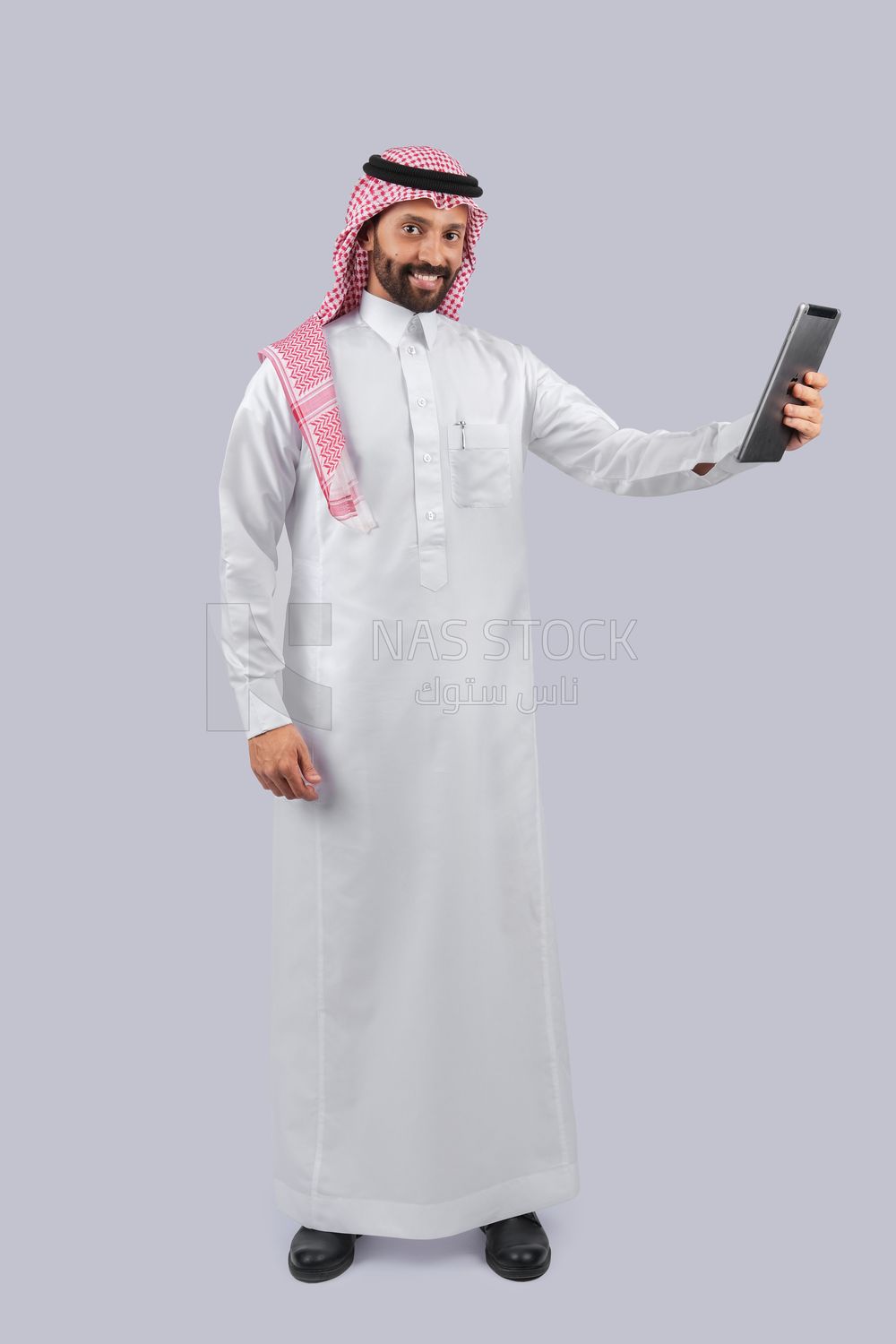 رجل خليجي يحمل جهاز لوحي