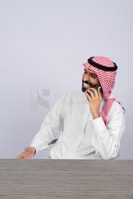 رجل خليجي يتحدث في الهاتف بسعادة