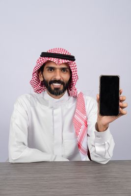 رجل خليجي يحمل هاتفًا محمولاً