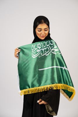 Saudi girl wearing the Gulf abaya and placing the Saudi flag on her shoulder