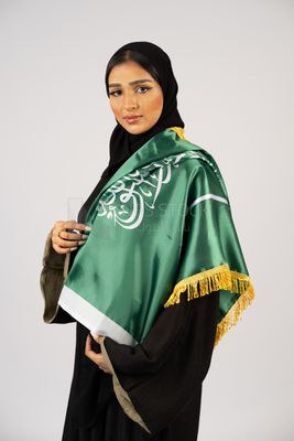 Saudi girl wearing the Gulf abaya and placing the Saudi flag on her shoulder