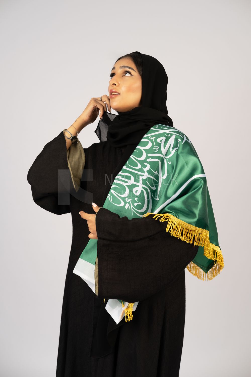 Saudi girl wearing the Gulf abaya and placing the Saudi flag on her shoulder