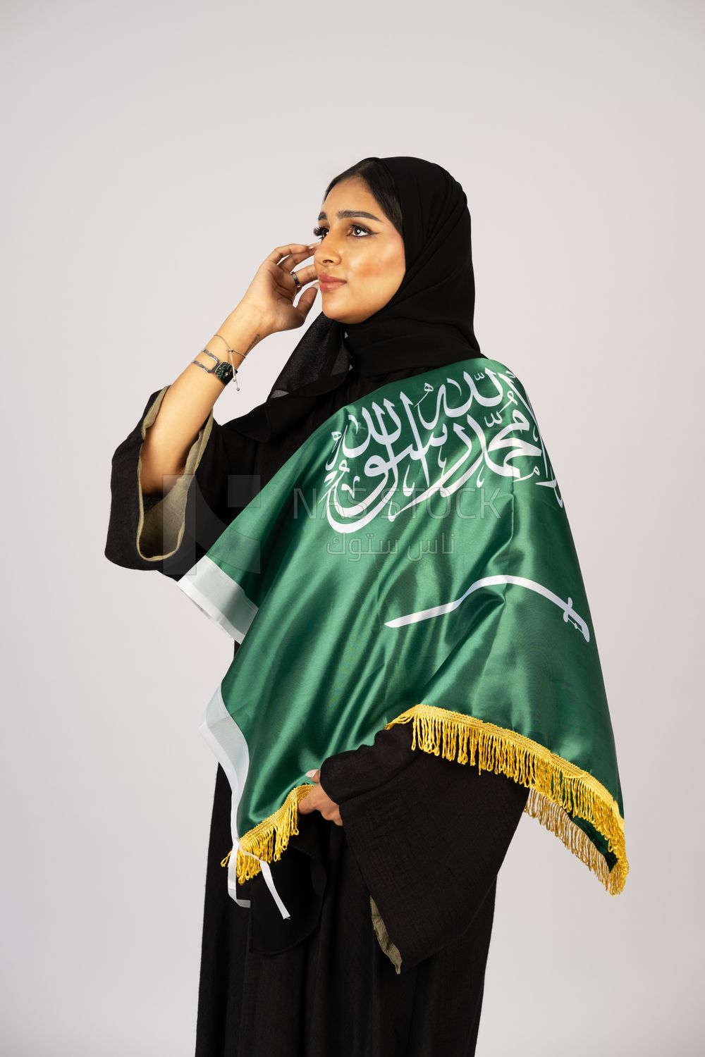 Saudi girl wearing the Gulf abaya and placing the Saudi flag on her shoulder