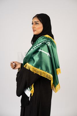 Saudi girl wearing the Gulf abaya and placing the Saudi flag on her shoulder