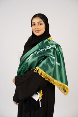 Saudi girl wearing the Gulf abaya and placing the Saudi flag on her shoulder
