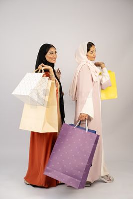 Two Gulf girls wearing Gulf abayas and carrying shopping bags