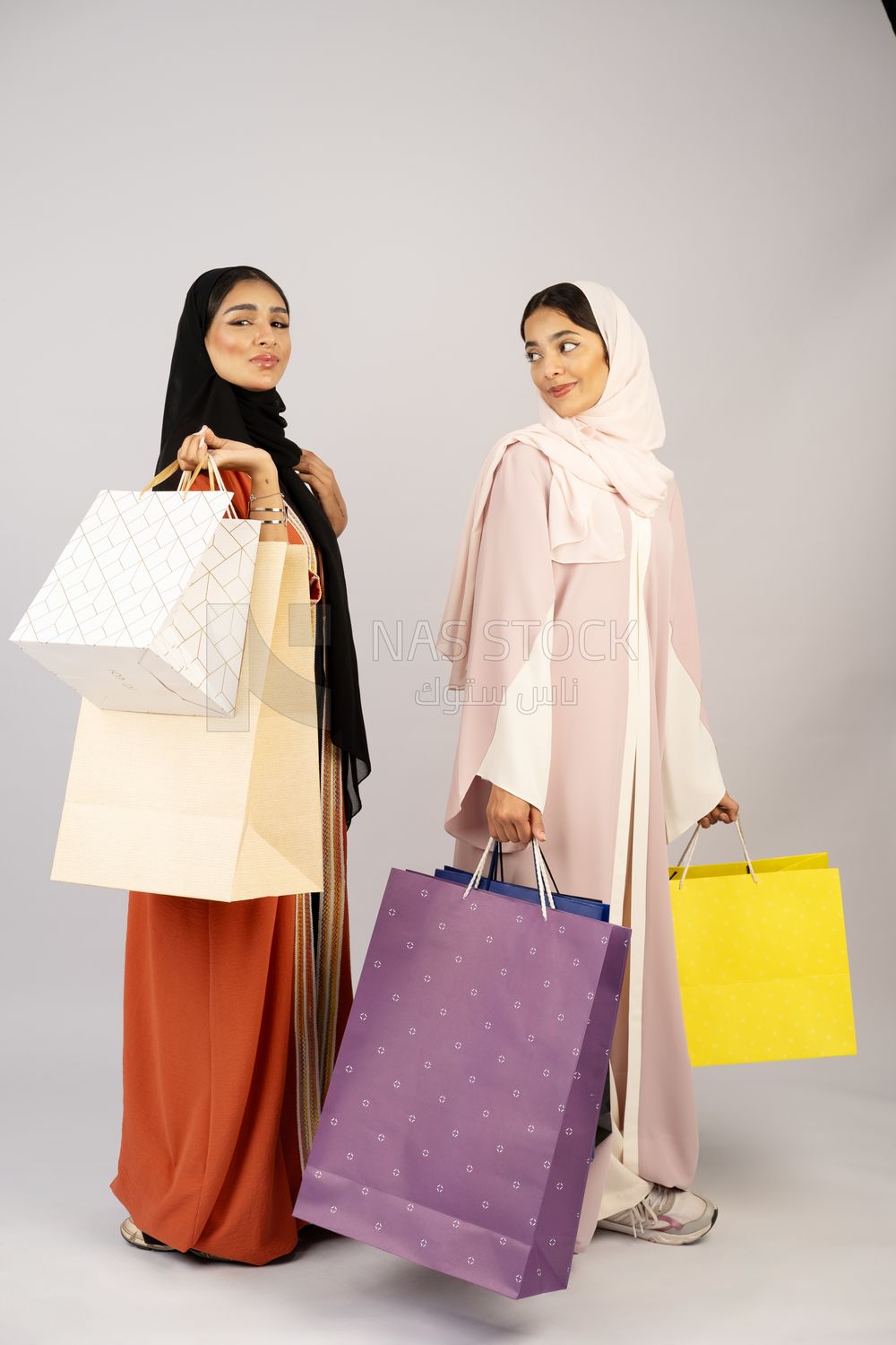Two Gulf girls wearing Gulf abayas and carrying shopping bags