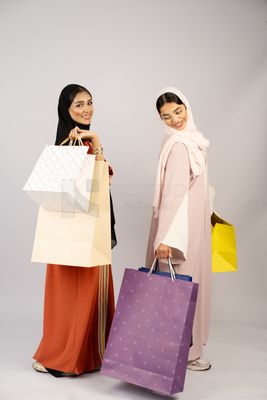 Two Gulf girls wearing Gulf abayas and carrying shopping bags