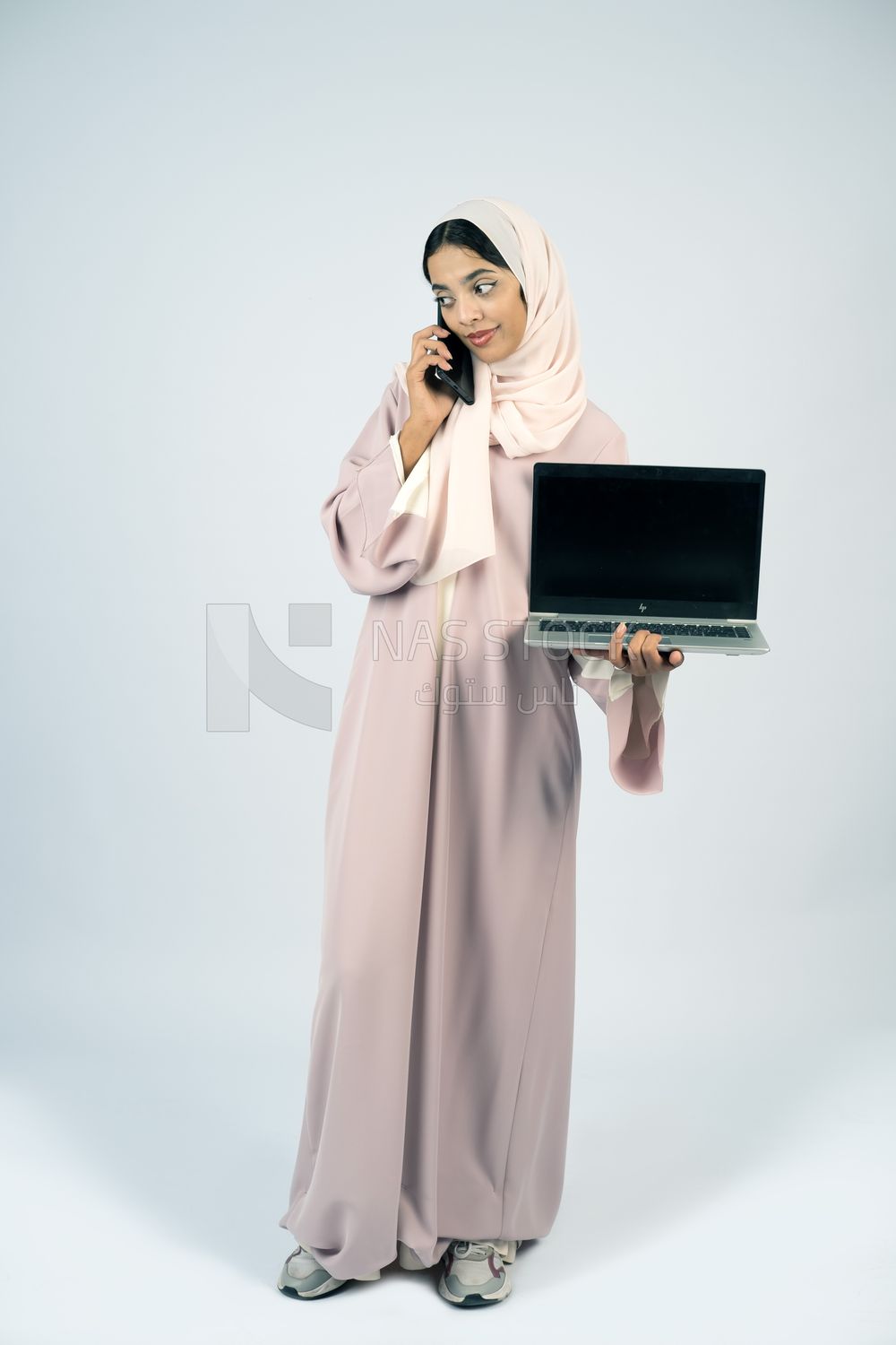 Gulf girl holding a laptop and talking on the phone