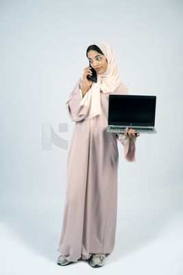 Gulf girl holding a laptop and talking on the phone