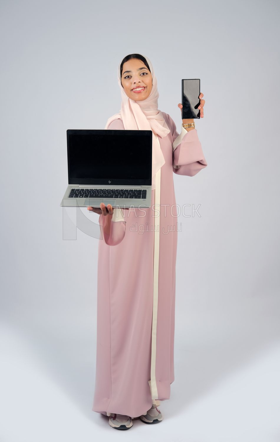 Gulf girl holding a laptop with a phone