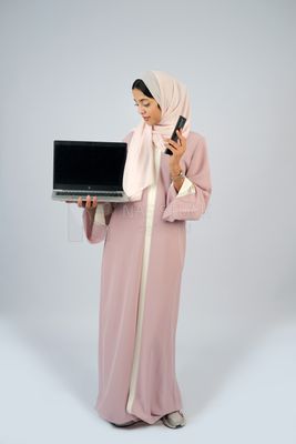 Gulf girl holding a laptop with a phone