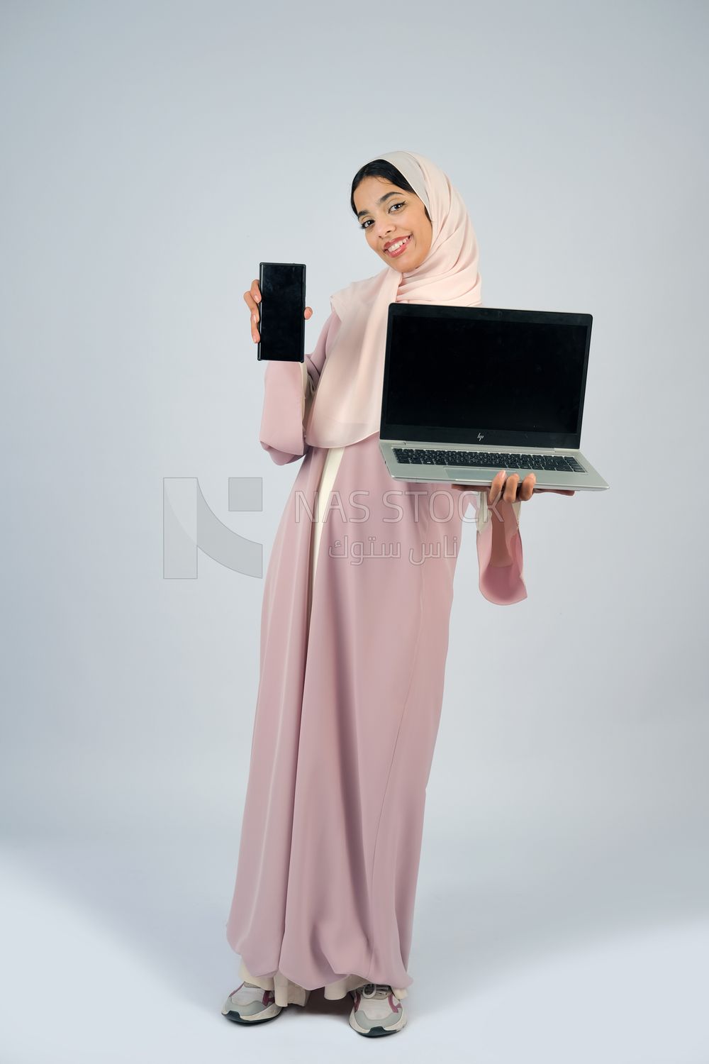Gulf girl holding a laptop with a phone