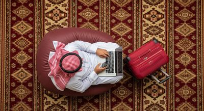 Gulf man using a computer with a red suitcase next to him