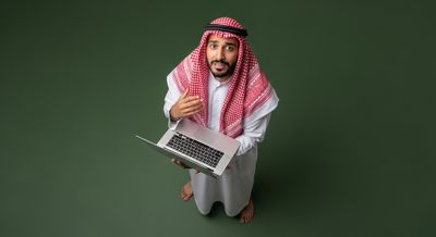 Gulf man holding a laptop and looking up