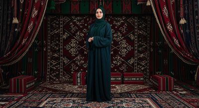 A woman wearing an abaya stands in the middle of an Arab council