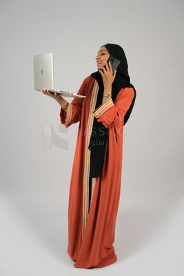 Gulf girl talking on the phone and holding a laptop