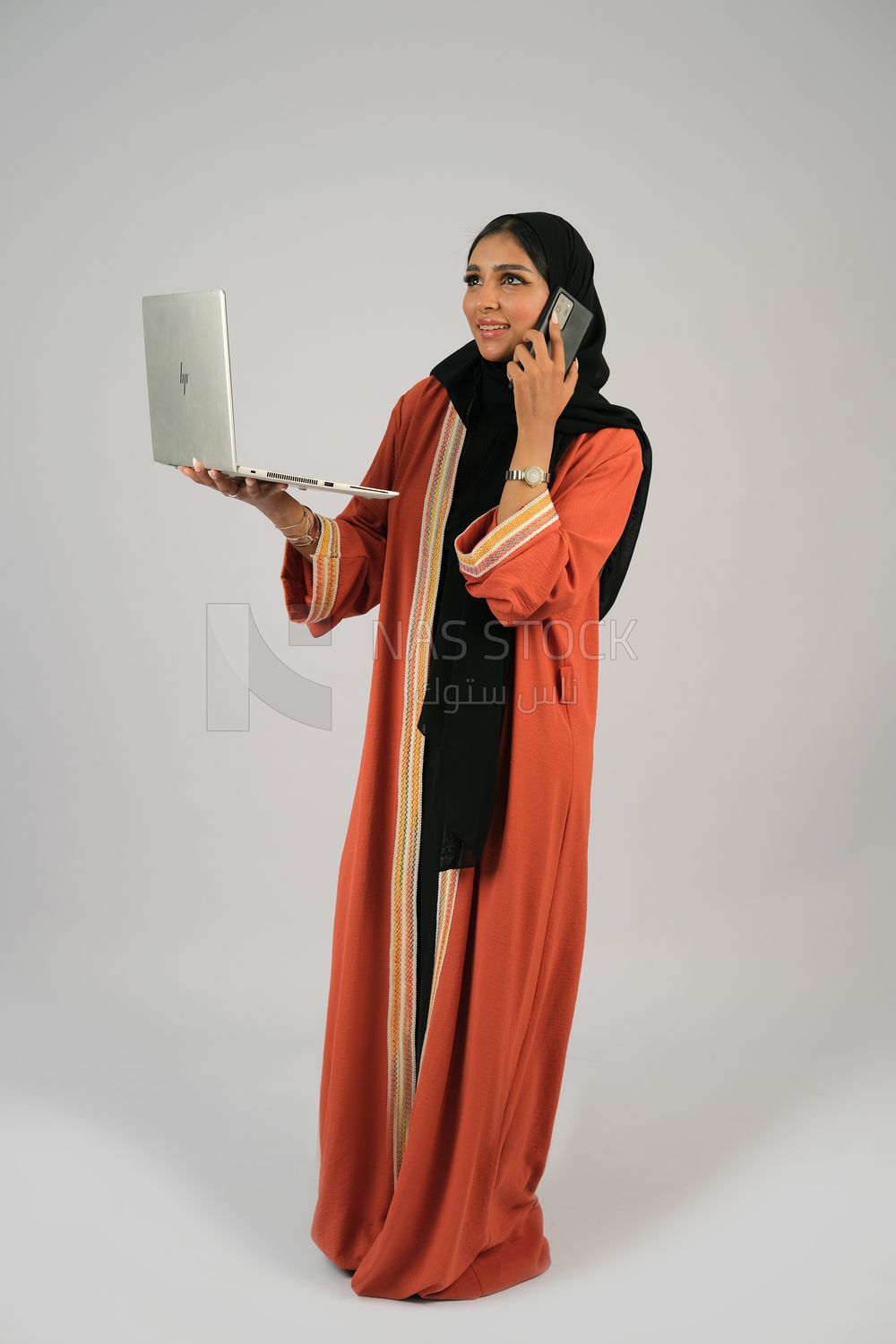 Gulf girl talking on the phone and holding a laptop