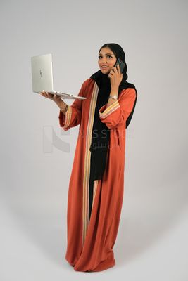 Gulf girl talking on the phone and holding a laptop