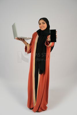 Gulf girl holding a phone and a laptop with a blank black screen