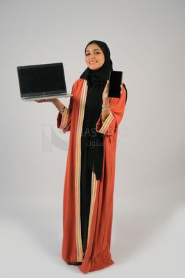 Gulf girl holding a phone and a laptop with a blank black screen