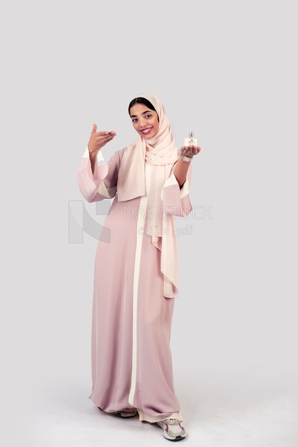 Gulf woman holding a bottle of perfume in her hand