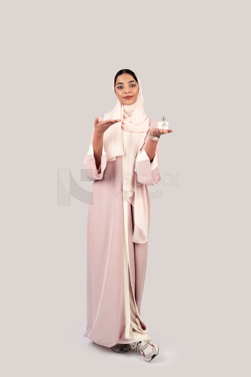 Gulf woman holding a bottle of perfume in her hand