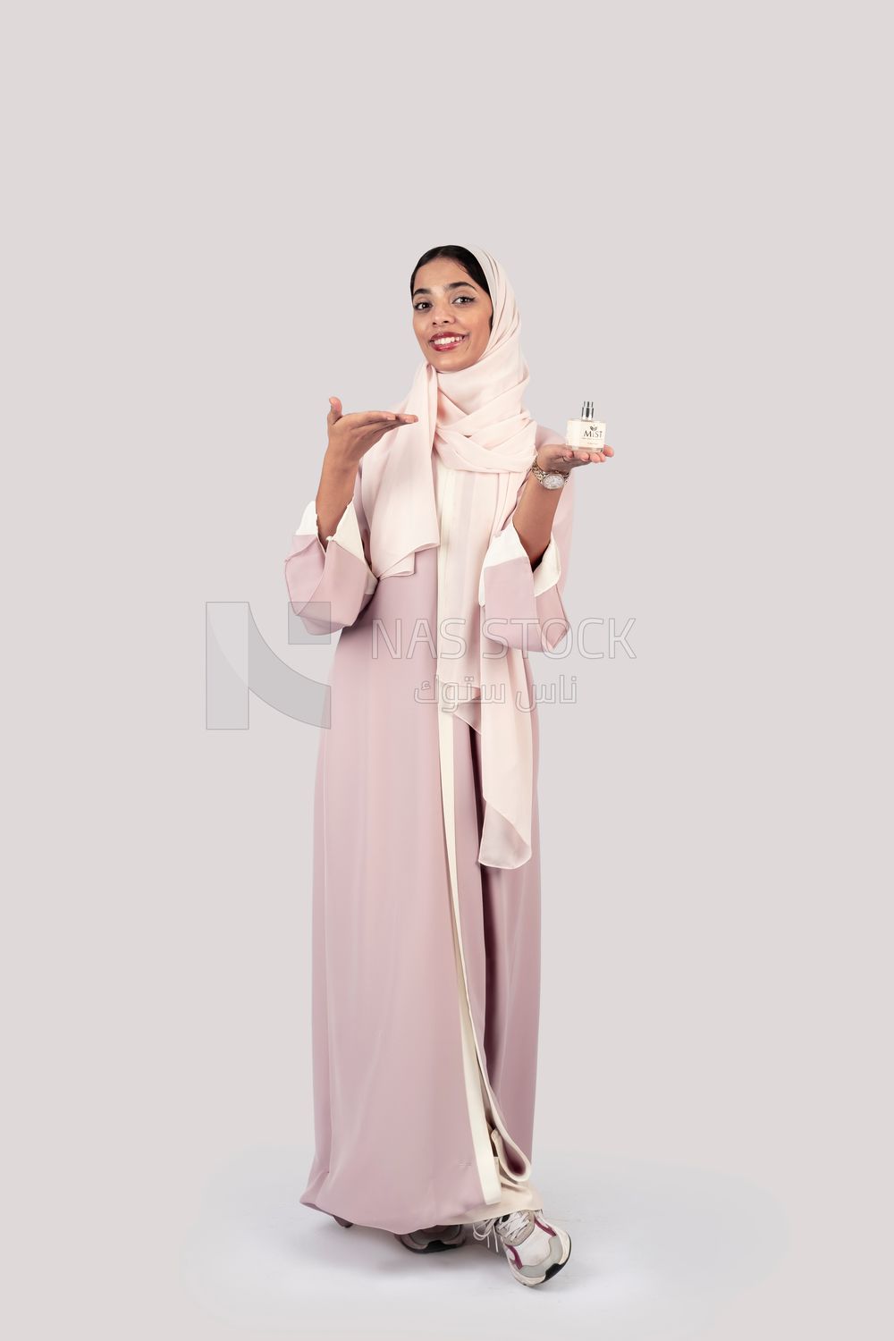 Gulf woman holding a bottle of perfume in her hand