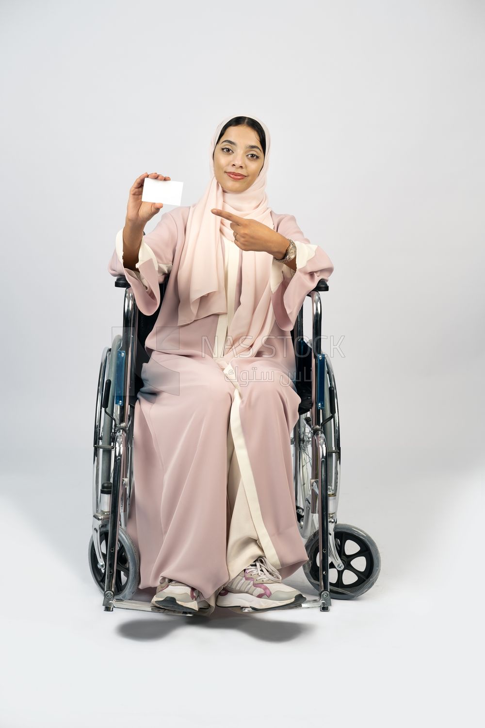 Girl sitting in wheelchair holding white card