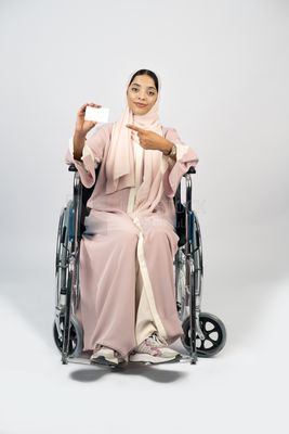 Girl sitting in wheelchair holding white card