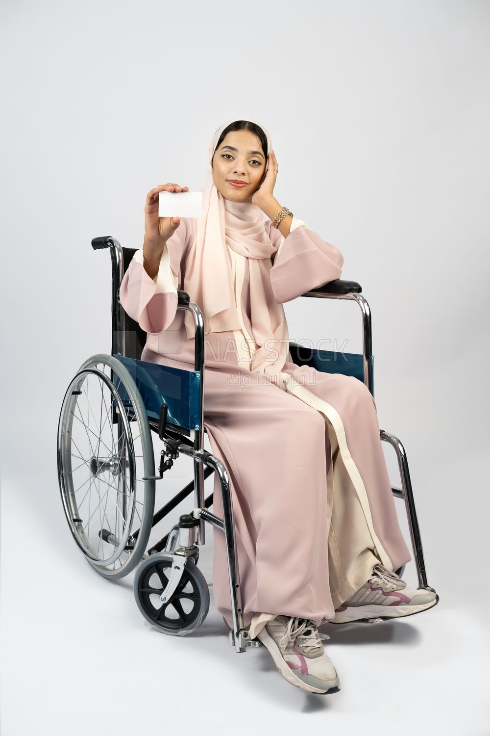 Girl sitting in wheelchair holding white card