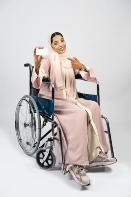 Girl sitting in wheelchair holding white card