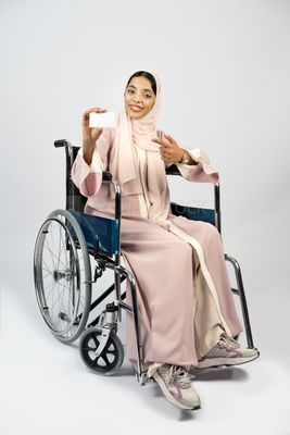 Girl sitting in wheelchair holding white card