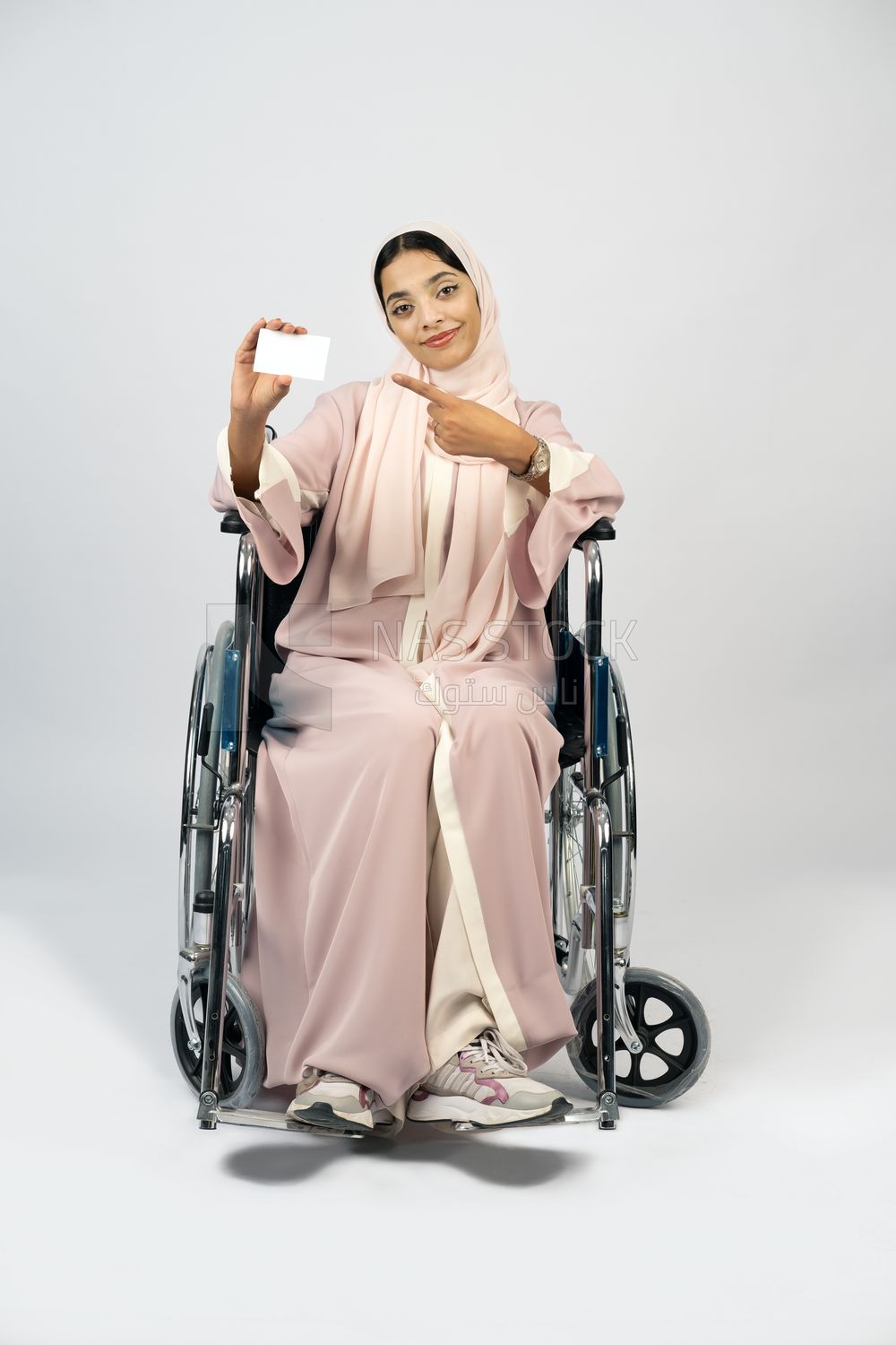 Girl sitting in wheelchair holding white card