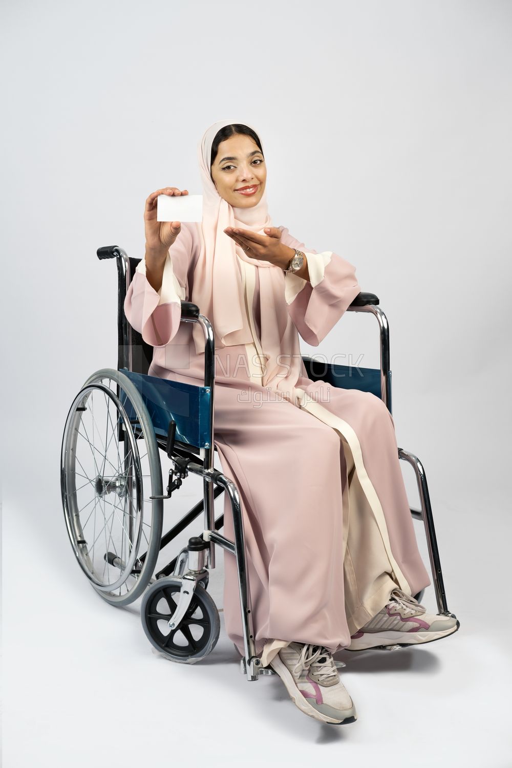 Girl sitting in wheelchair holding white card