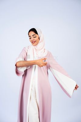 Gulf woman wearing abaya and hijab spraying perfume